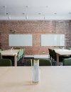 Empty classroom with tables, chairs, and 2 white boards hanging on a brick walll