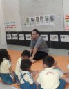 Male teacher sitting on mat in front of a class full of small kids
