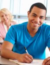 Young male writing on a desk and smiling
