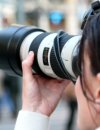 Back of a woman holding a camera with a long lens up to take a picture