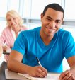 Young male writing on a desk and smiling