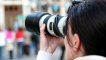 Back of a woman holding a camera with a long lens up to take a picture