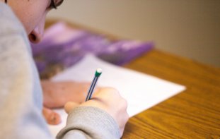 Student writing on a piece of paper at desk