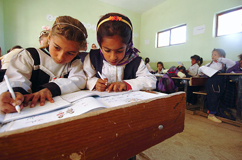 Two young girls at desk working together in a classroom